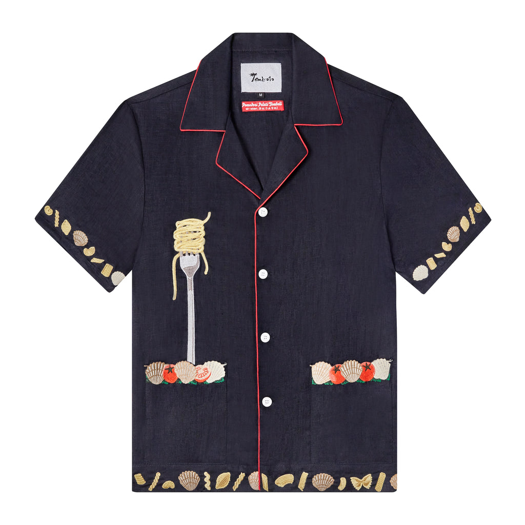 Front view of our navy Vongole shirt with red piping and white buttons with edge embroidered patch pockets featuring cherry tomatoes and clams, also has an embroidered fork with twirl of spaghetti protruding from wearer's right pocket, and shows assorted pasta shapes and clams embroidered on the bottom hem and sleeve openings
