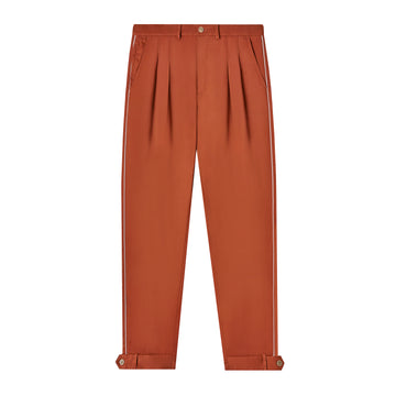 Front view of rust-colored traveler pants including view of two tuck pleats into waistband of each side. 