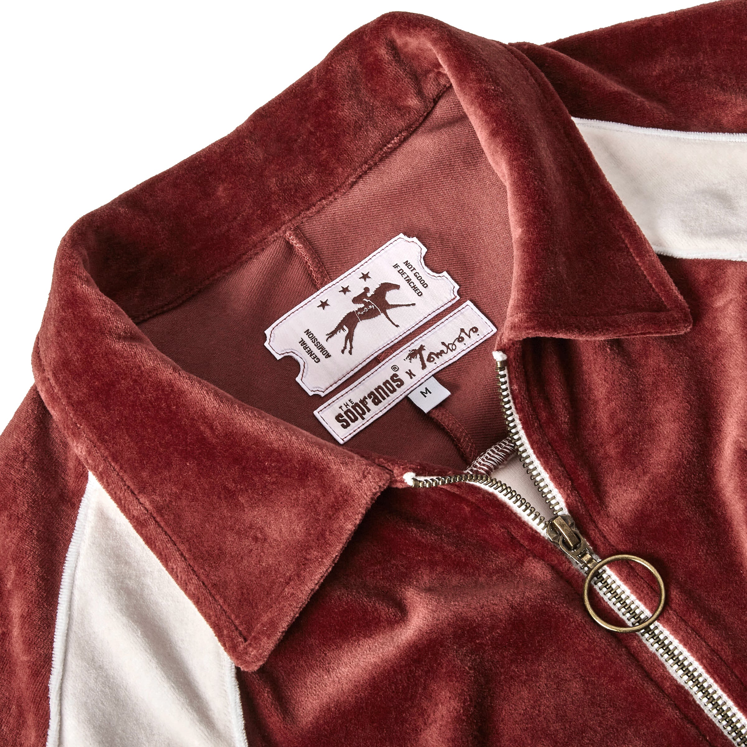 Close-up product image of 'The Sopranos' Pie-O-My Track Jacket that highlights its brass full-length zipper and custom woven The Sopranos x Tombolo and admission ticket interior labels