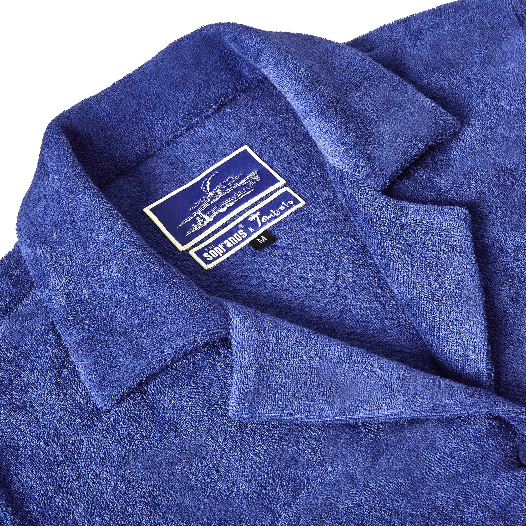 Close-up shot of 'The Sopranos' Vesuvio Cabana ~ Crop Cut that emphasizes the Custom 'The Sopranos' x Tombolo woven interior label and distinct V shape collar.