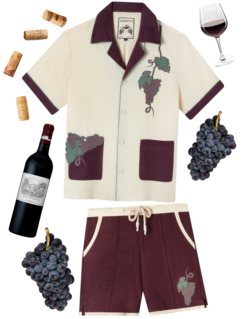 Lay-flat image of the wine-themed linen Tombolo set surrounded by wine ephemera (ie. wine glass, grapes, corks, and wine bottle)