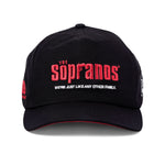 Front-facing image of 'The Sopranos' 25th Anniversary 5-Panel Souvenir Cap with a black base and red lettering in the center saying: "The Sopranos" in the classic Sopranos font, and white lettering saying: "We're just like any other family' directly below that with a red accent on the inside of the brim, all shot on a white background.