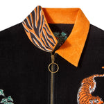 Close-up of a black terry cloth shirt with a bright orange collar. The inner collar features a tiger stripe pattern. Visible gold zipper with circular pull, partial tiger embroidery, and green ivy detailing on the shirt.