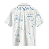 The back of a white short-sleeve shirt featuring abstract blue brushstroke designs of flowers, birds, and leaves, with a row of teardrop shapes across the upper back and stitched trim on the sleeves.