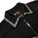 Close-up of black shirt collar with white trim, a Tombolo Surf Club label inside, and a silver surfboard-shaped zipper pull.