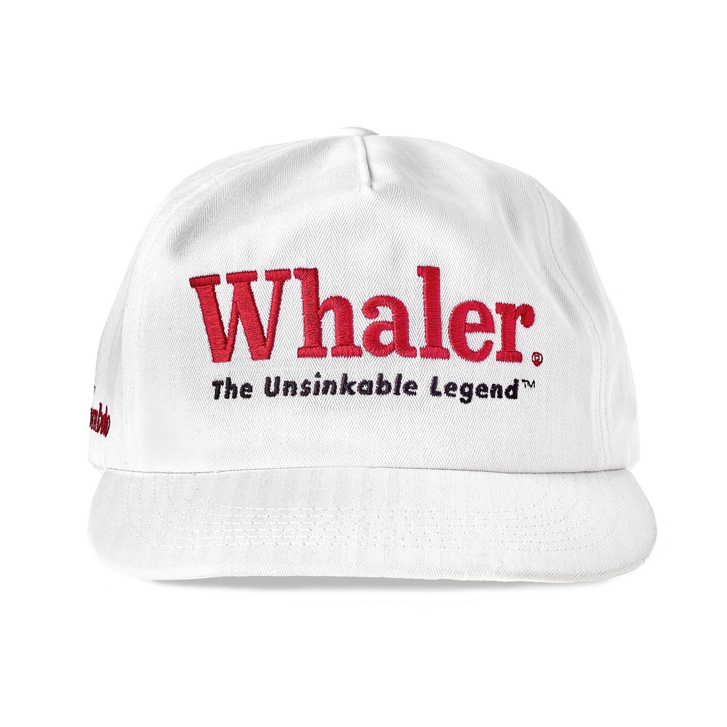 White five-panel cap with red embroidered text reading 'Whaler' and black text below reading 'The Unsinkable Legend.' Shown from the front.