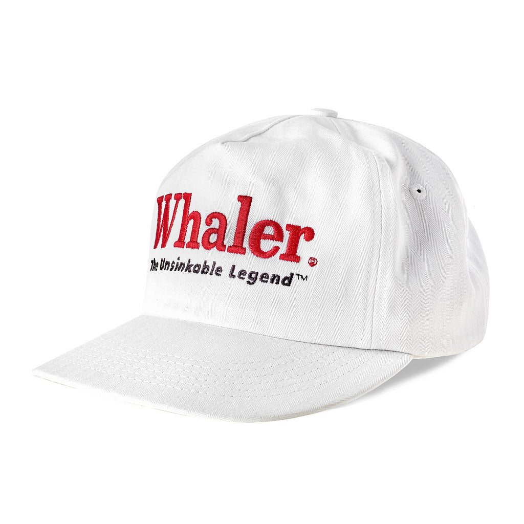 White five-panel cap shown from an angle, with red embroidered text reading 'Whaler' and smaller black text below reading 'The Unsinkable Legend.'