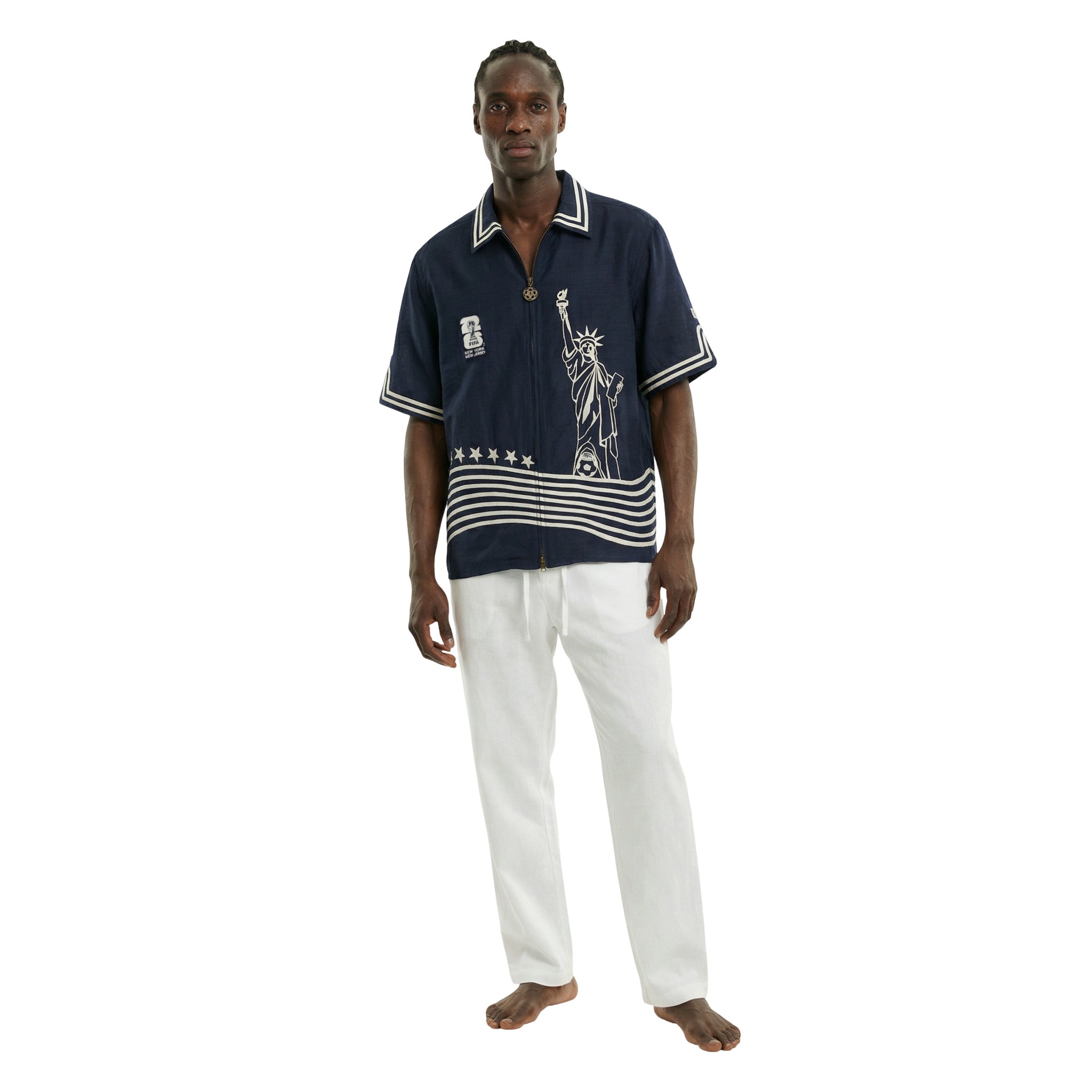 Man wearing a navy blue Fifa World Cup shirt and white pants on a white background.