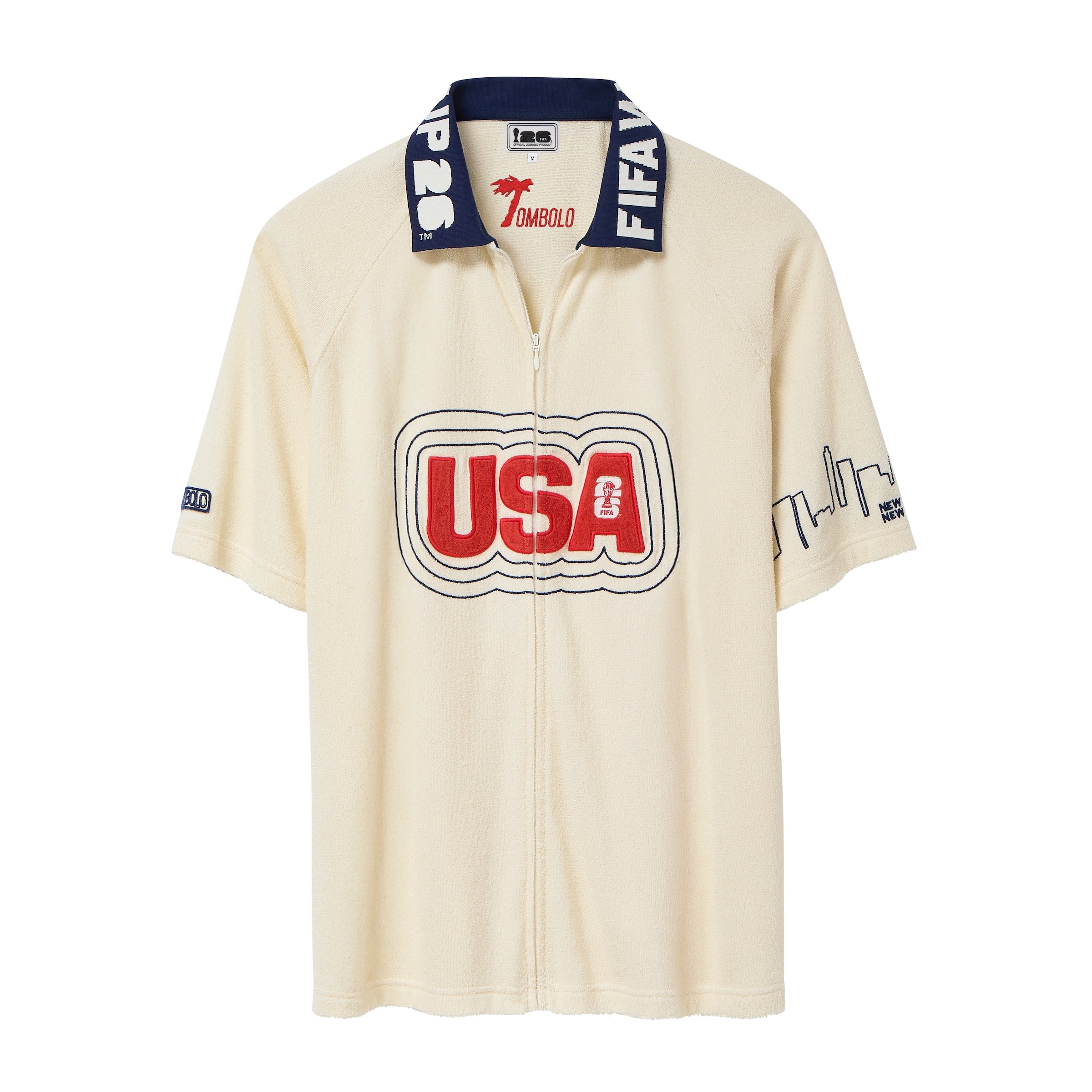 Cream short-sleeve terry cloth zip-front shirt with large red “USA” appliqué across the chest, navy contrast collar with white lettering, and embroidered skyline graphics on the sleeves.