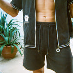 Cropped view of male model wearing the green terry cloth gambling themed set. Top is unzipped fully. 