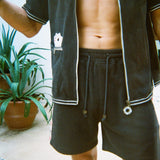 Cropped view of male model wearing the green terry cloth gambling themed set. Top is unzipped fully. 