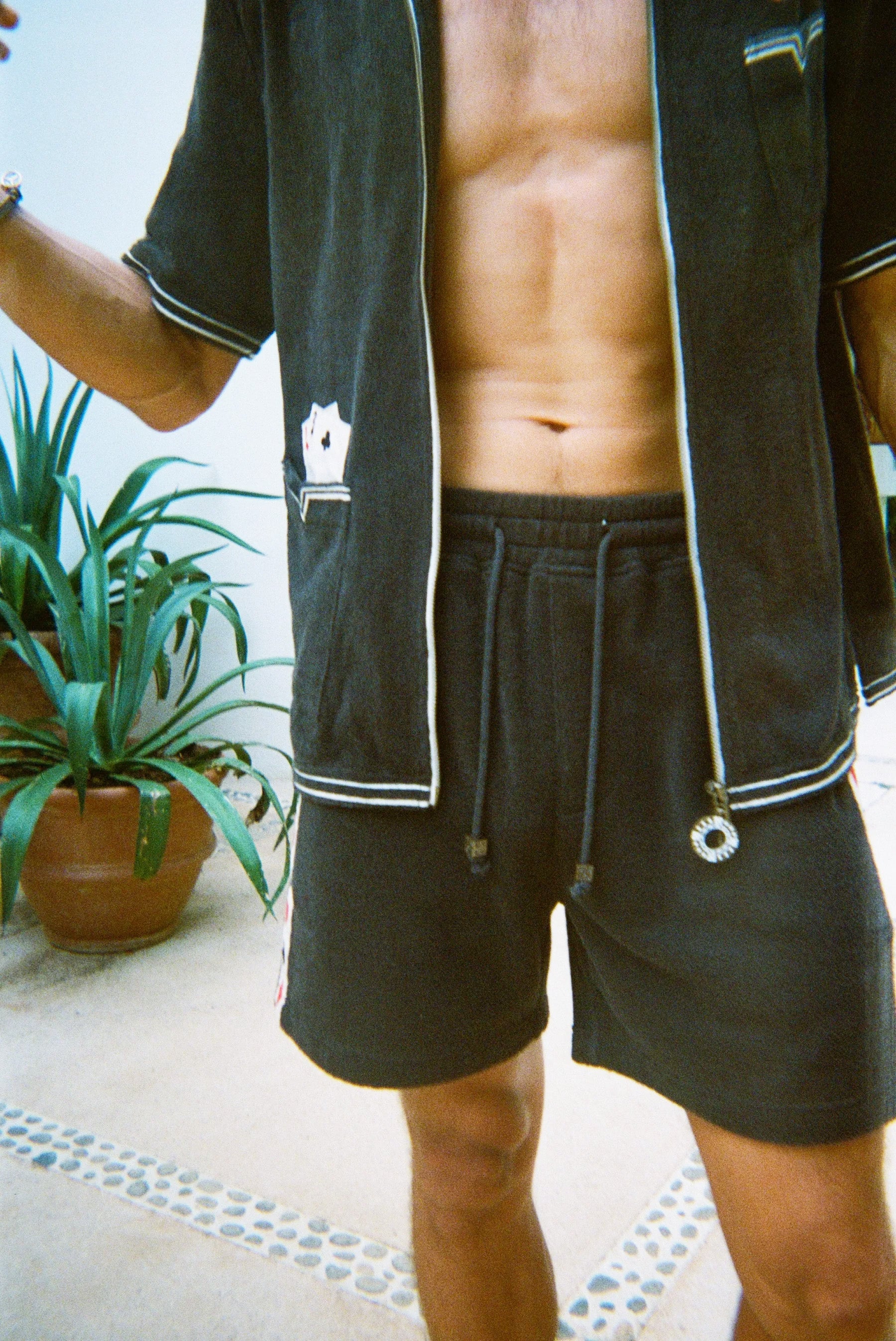 Cropped view of male model wearing the green terry cloth gambling themed set. Top is unzipped fully. 