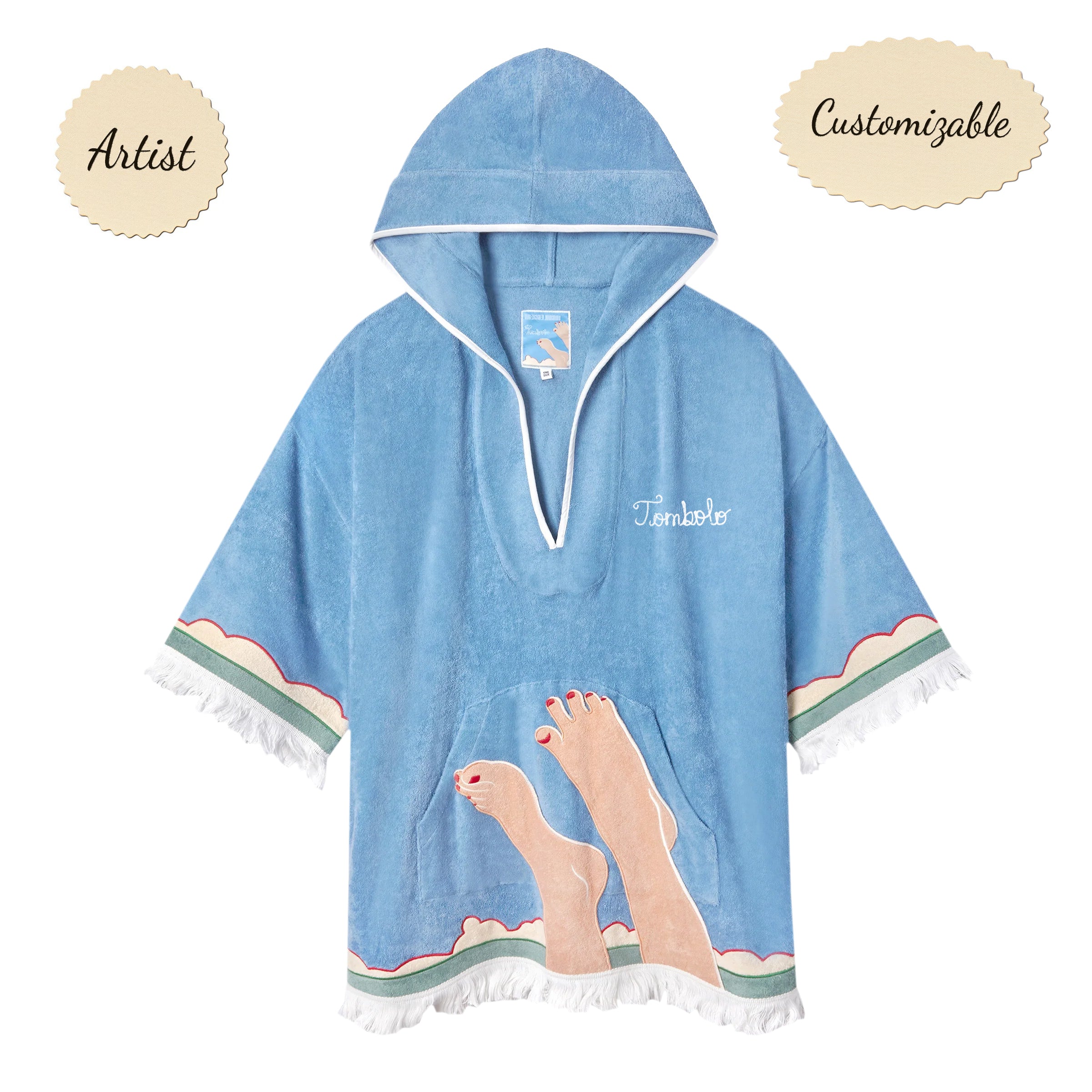 Sky blue terrycloth poncho with white fringe and trim, featuring an embroidered design of legs with red-painted toenails and waves along the hem. 'Tombolo' is stitched in white on the chest.
