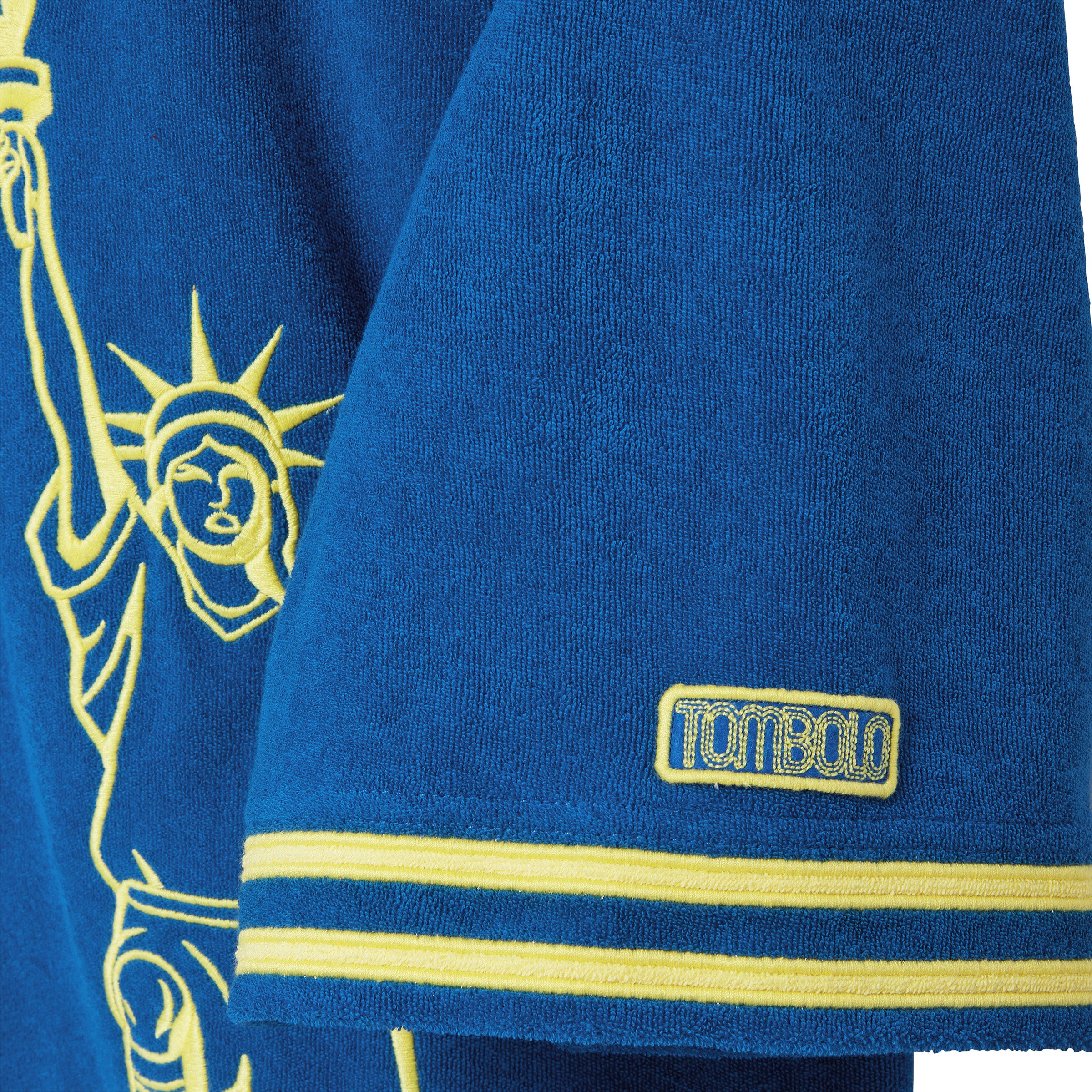 Blue sports jersey with yellow details and Statue of Liberty design, featuring a Tombolo patch.