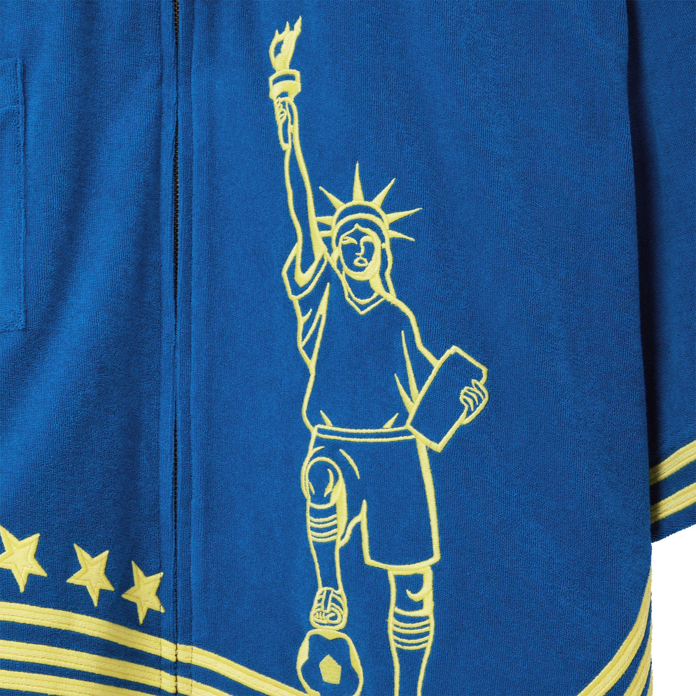 Blue beach towel top with yellow outline of the Statue of Liberty and stars design.