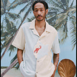 Male model with dreadlocks wearing the 'Hermit Crabana' Cabana with khakis, shot on a background of palm trees and blue skies.