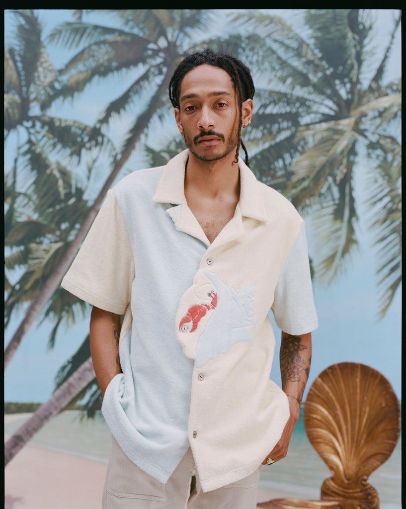 Male model with dreadlocks wearing the 'Hermit Crabana' Cabana with khakis, shot on a background of palm trees and blue skies.