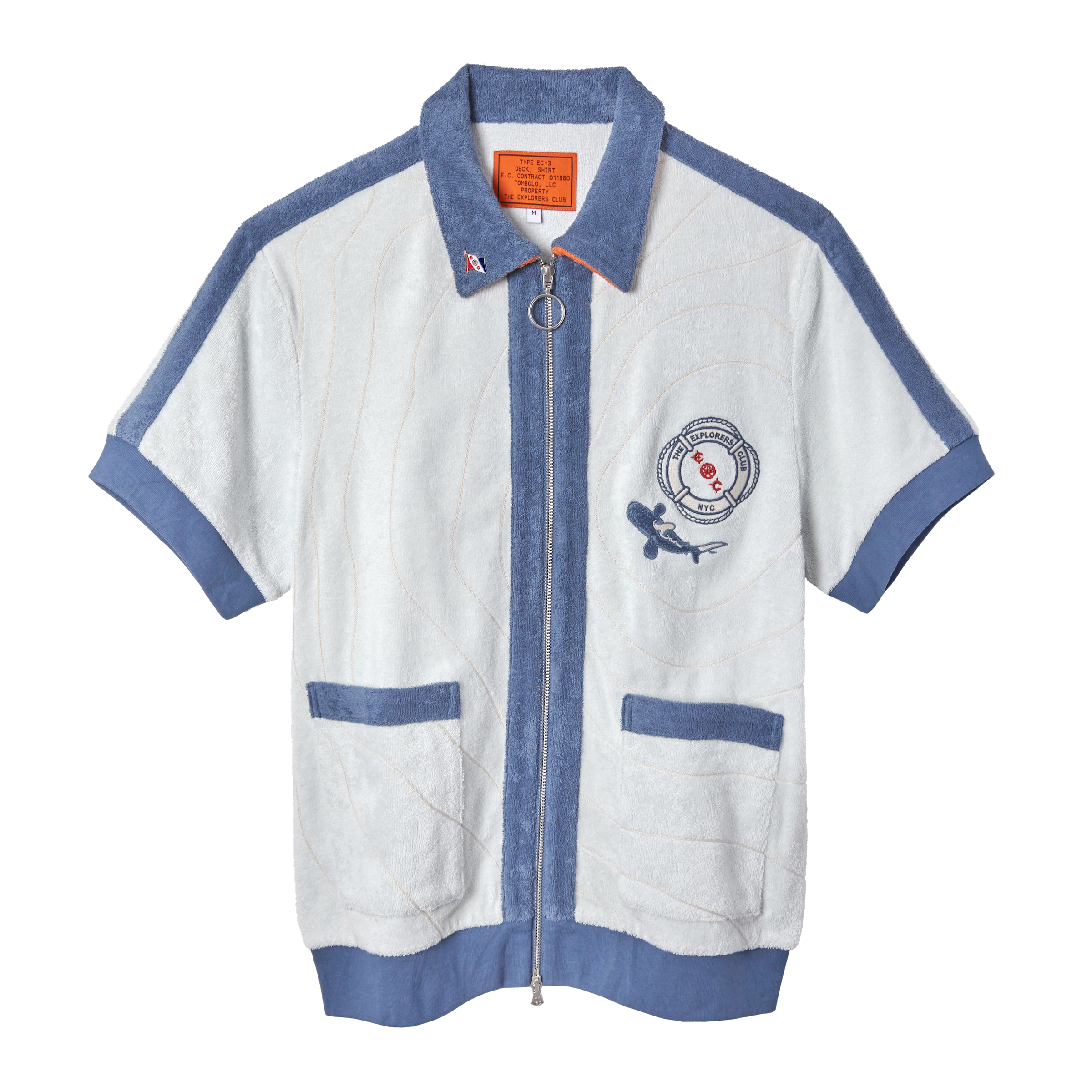 Short-sleeved zip-up terry cloth shirt in white with blue trim and piping. Features two front pockets, a ring zipper pull, and a chest patch with “The Explorers Club NYC,” the letters “E” and “C,” and a small shark illustration.
