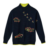 Navy blue knit sweater with neon yellow and red embroidered fish and lettering. Features labeled fish including “Striped Bass,” “Atlantic Cod,” “Sardines,” and a large “Great White Shark” with the word “Human” inside. Neon yellow accents line the collar, cuffs, and hem.