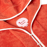 Close-up product image of the 'Scallop' Beach Towel Top's custom woven interior label saying 'Tombolo Poncho,' in addition to the two button and loop closures on collar opening