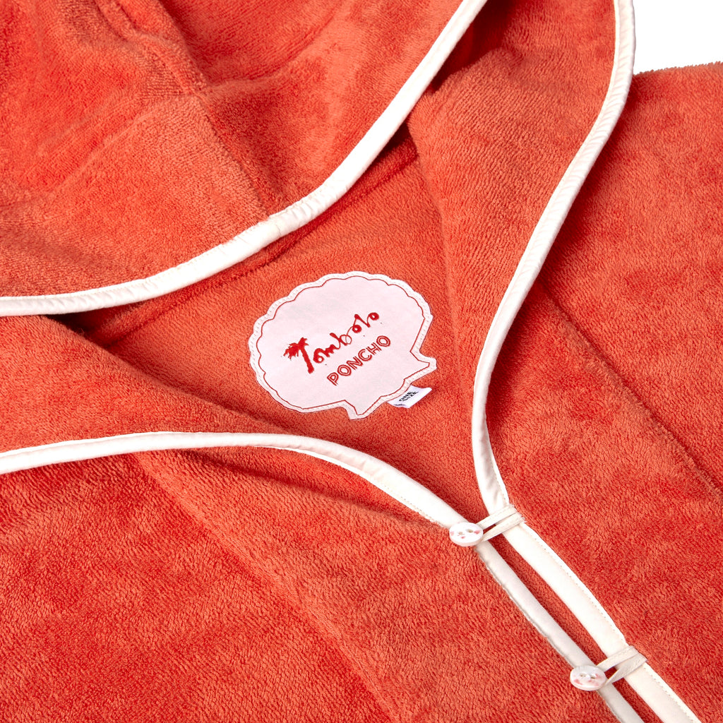 Close-up product image of the 'Scallop' Beach Towel Top's custom woven interior label saying 'Tombolo Poncho,' in addition to the two button and loop closures on collar opening