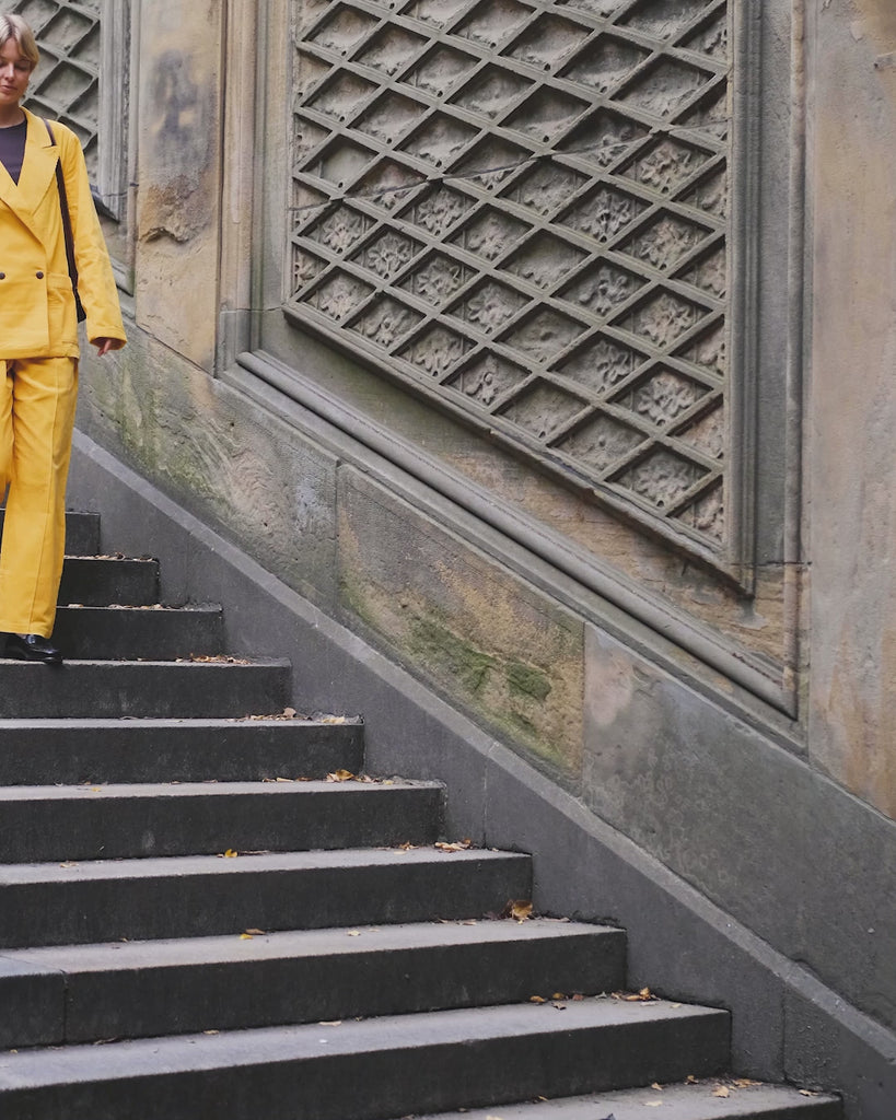 Woman walking downstairs, wearing the full Saffron Corduroy Easy Going Suit.