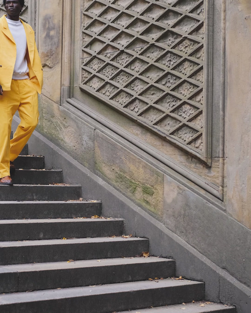 Man walking downstairs, wearing the full Saffron Corduroy Easy Going Suit.