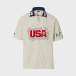 Video of Cream short-sleeve terry cloth zip-front shirt with large red “USA” appliqué across the chest, navy contrast collar with white lettering, and embroidered skyline graphics on the sleeves.