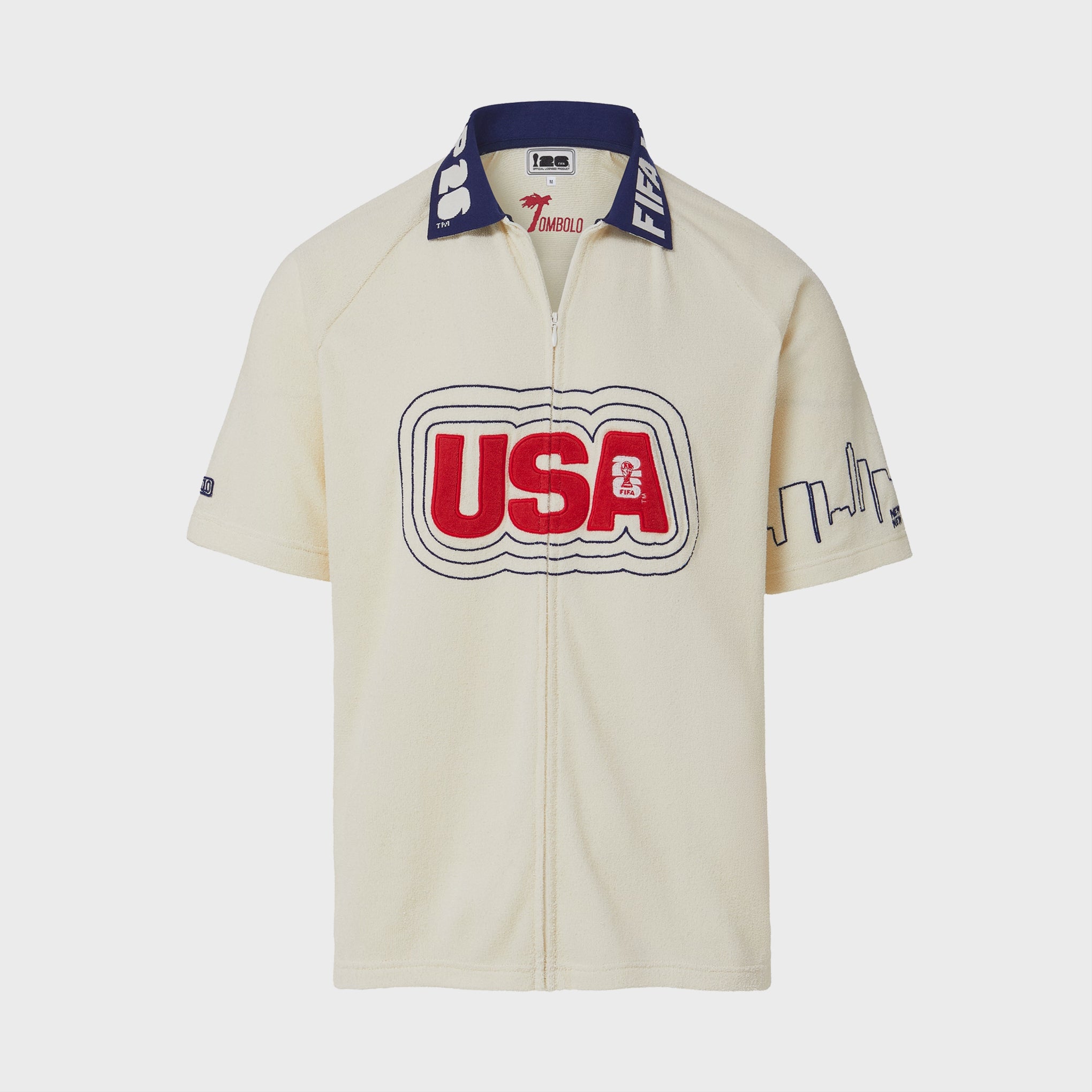 Video of Cream short-sleeve terry cloth zip-front shirt with large red “USA” appliqué across the chest, navy contrast collar with white lettering, and embroidered skyline graphics on the sleeves.