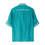 Teal short sleeve cabana shirt back with white FIFA World Cup 26 text across shoulders and striped trim at collar and sleeves.