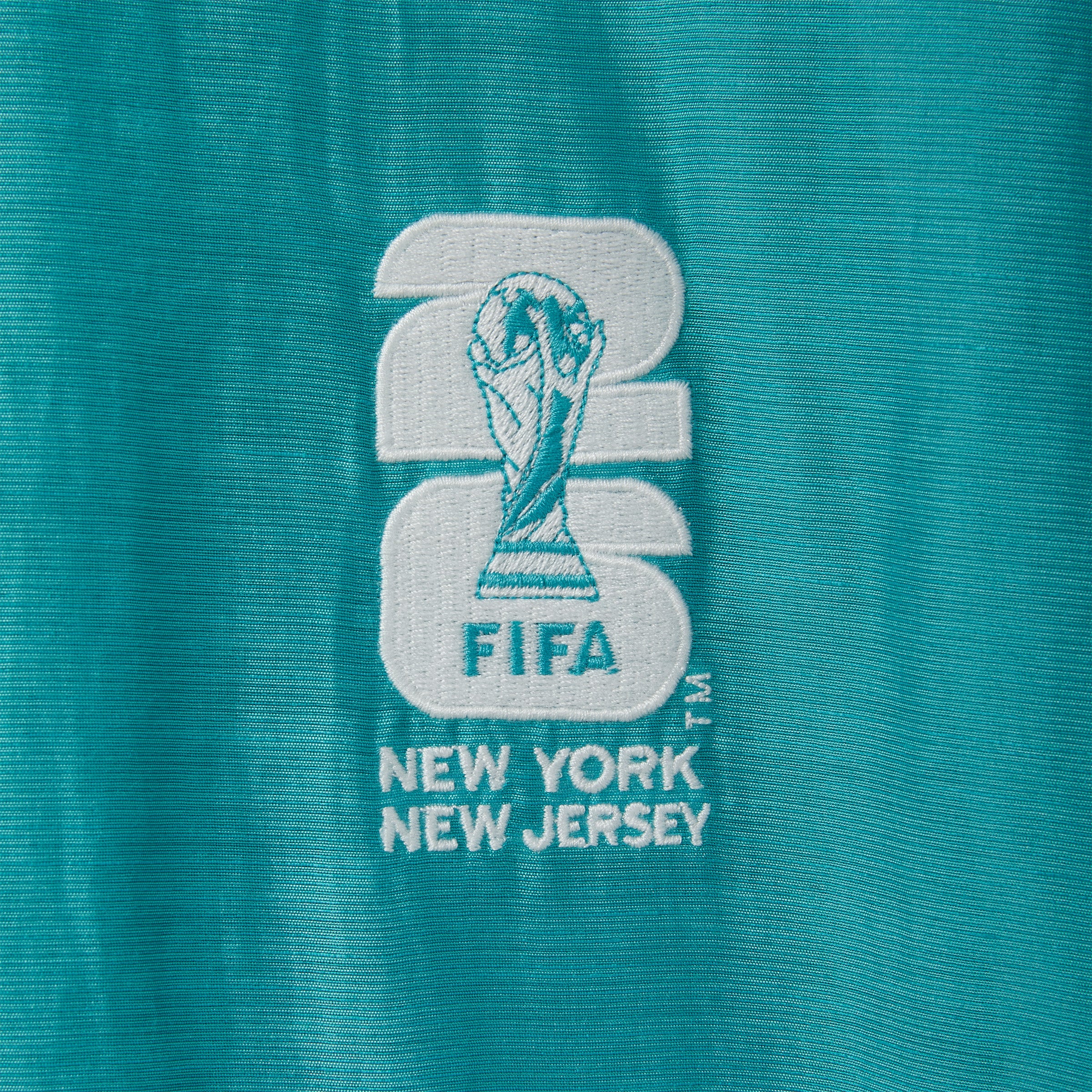 Embroidered FIFA logo on a teal fabric.