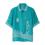Teal short sleeve zip-front shirt with white embroidery featuring the Statue of Liberty, stars, and FIFA World Cup 2026 New York New Jersey graphics.