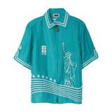 Teal short sleeve zip-front shirt with white embroidery featuring the Statue of Liberty, stars, and FIFA World Cup 2026 New York New Jersey graphics.