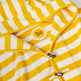 Close-up product image of the 'Saffron Stripe' beach towel top's circular interior tag with sun pattern and bamboo toggles and loop holds.