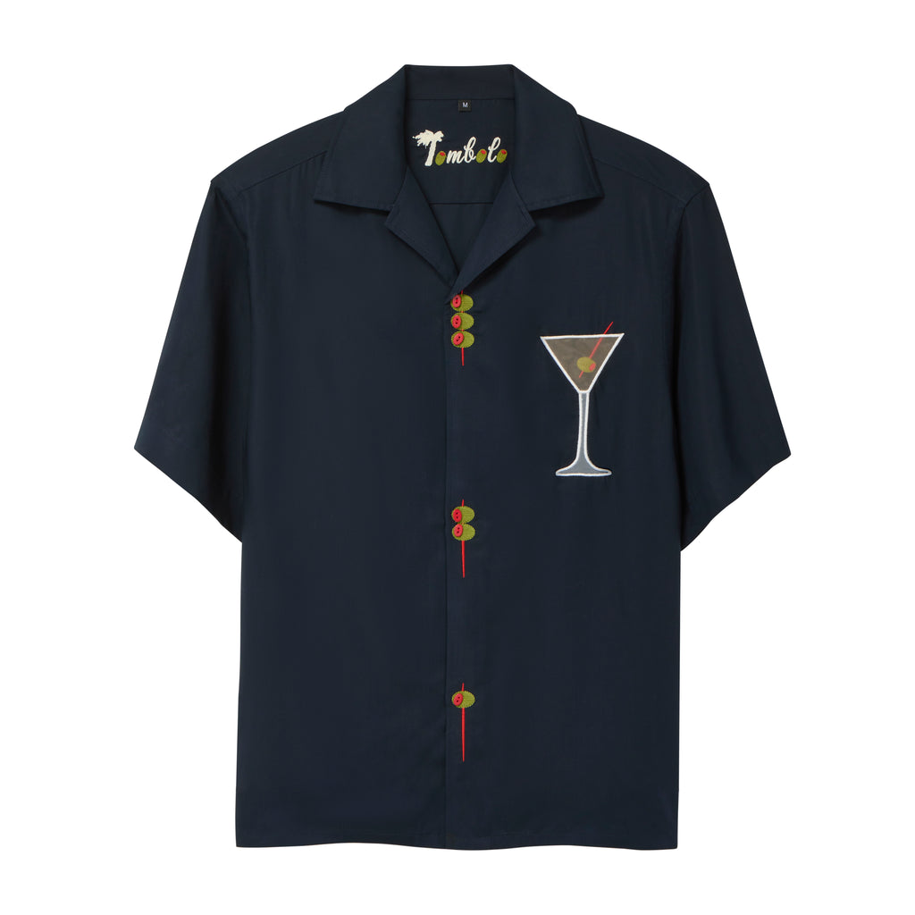 A navy blue short-sleeve button-down shirt with playful detailing: embroidered olive skewers act as buttons down the front, and a white martini glass with an olive garnish is embroidered on the chest. 