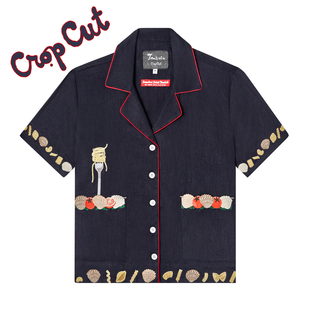 Crop cut version of our navy Vongole shirt with red piping and white buttons with edge embroidered patch pockets featuring cherry tomatoes and clams, also has an embroidered fork with twirl of spaghetti protruding from wearer's right pocket, and shows assorted pasta shapes and clams embroidered on the bottom hem and sleeve openings