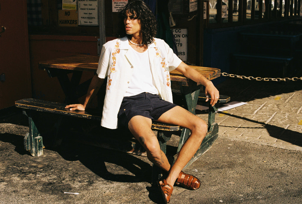 man sits on picnic table and looks off screen