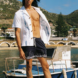 male model letting marie de buttet cabana billow open in the wind with swim trunks on