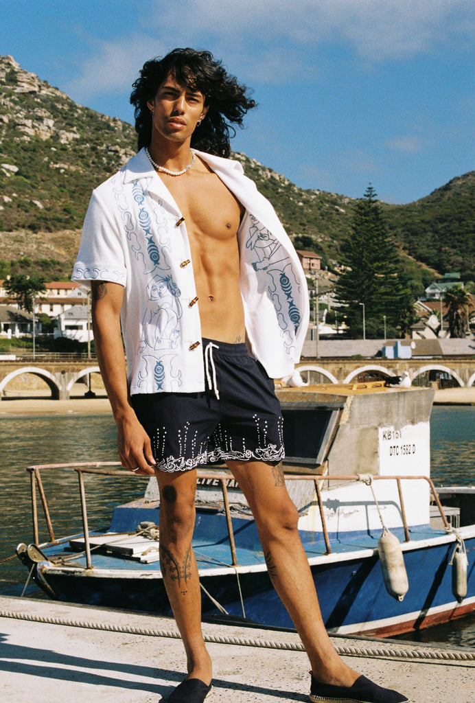 male model letting marie de buttet cabana billow open in the wind with swim trunks on