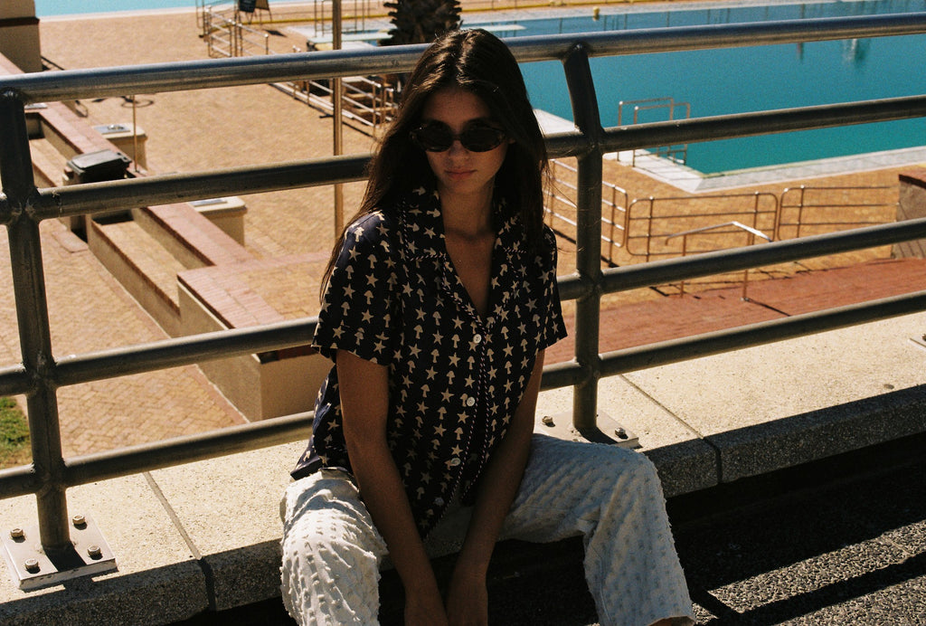 Female model posing in shirt near a pool