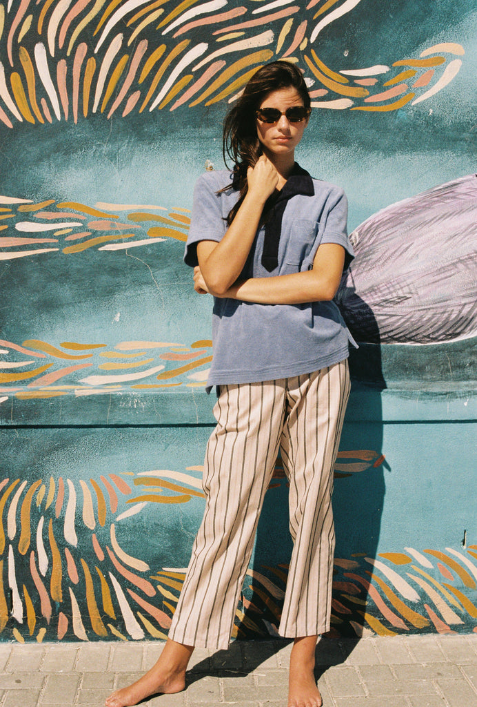 Woman standing against wall wearing striped pants 