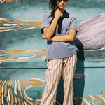 Female model wearing shirt against patterned wall with hand holding hair