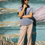 Female model wearing shirt against patterned wall with hand holding hair