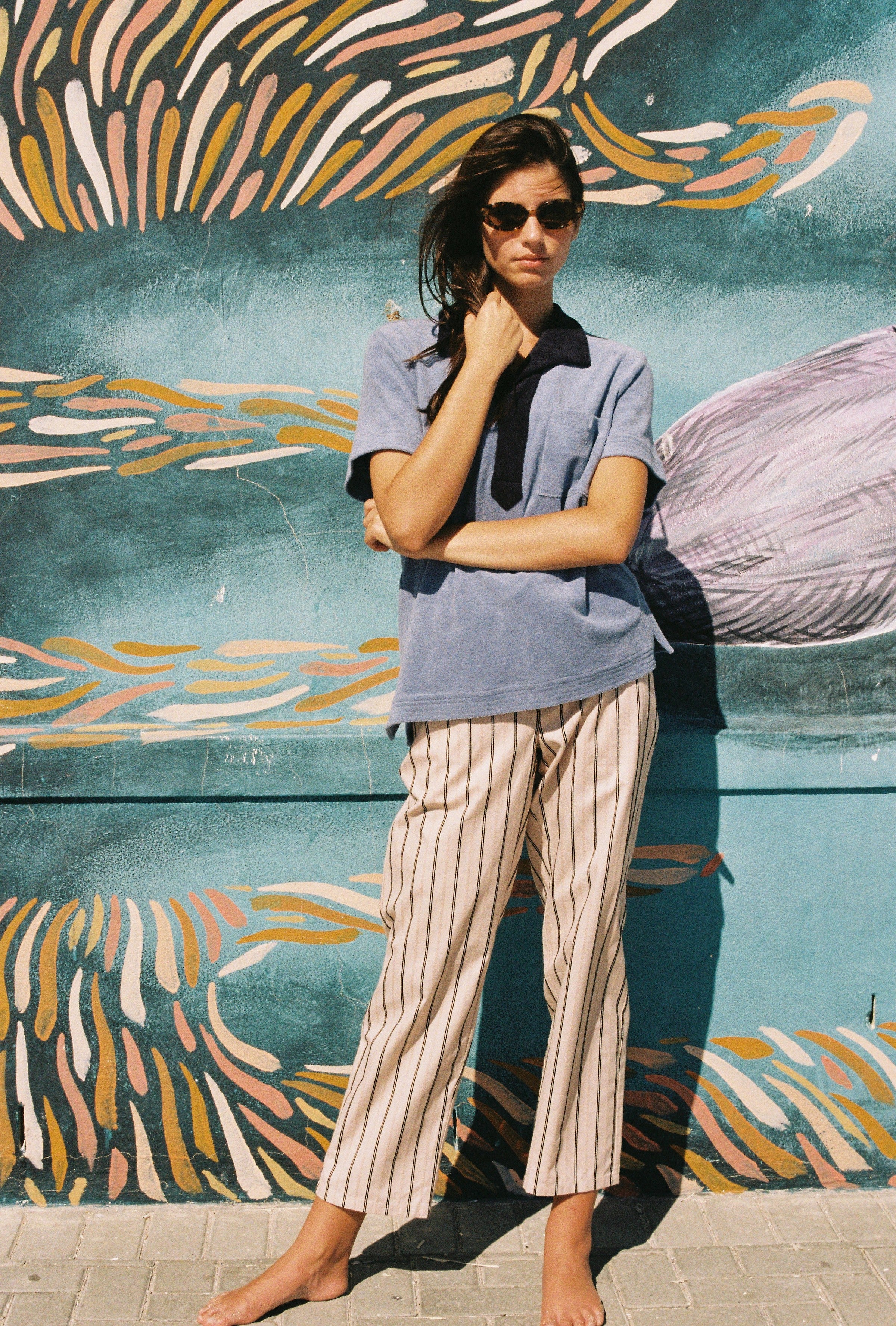 Female model wearing shirt against patterned wall with hand holding hair