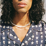 Close up of male model wearing shirt with a beaded necklace