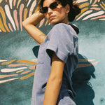 Female model weraing polo looking over right shoulder holding hair up