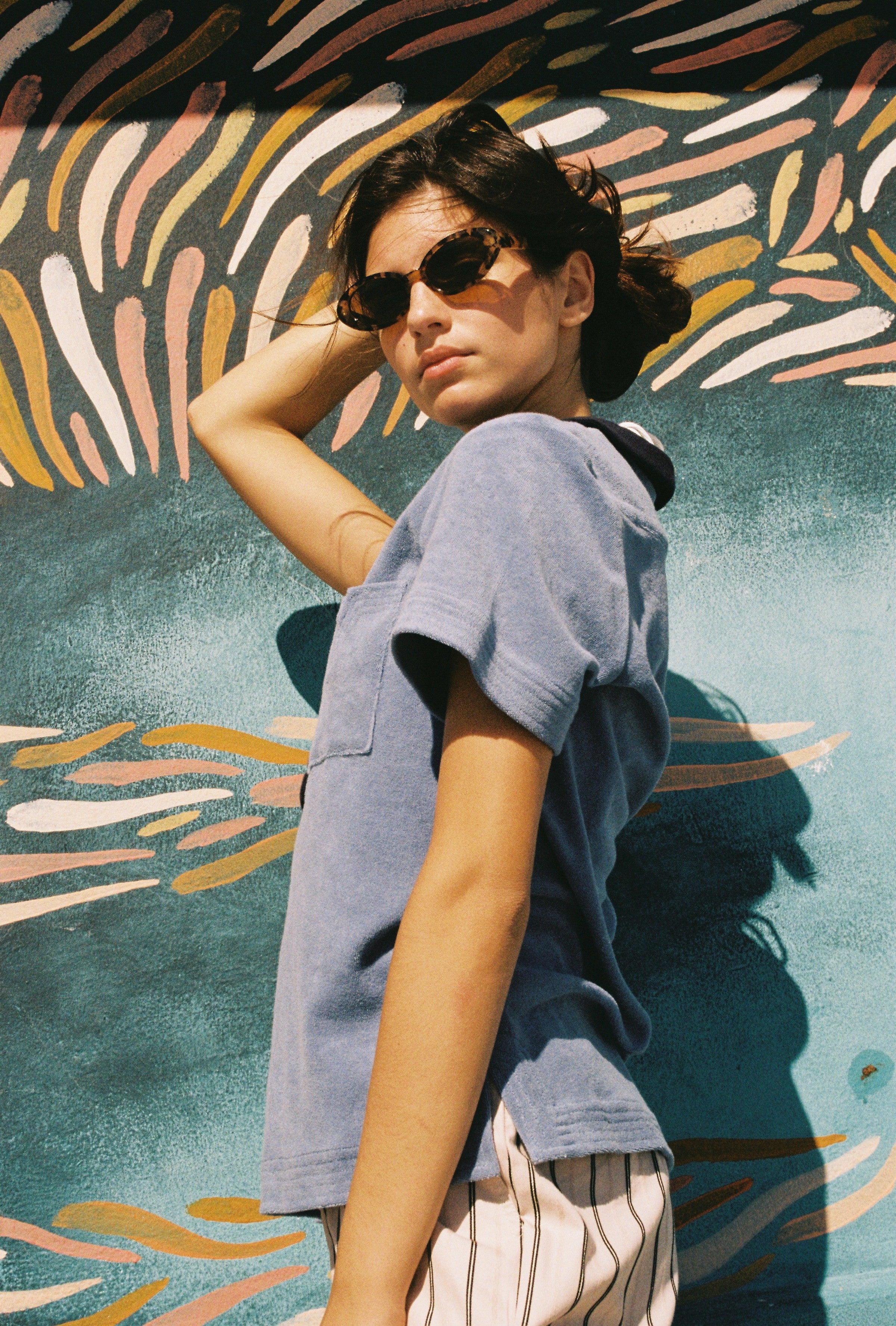 Female model weraing polo looking over right shoulder holding hair up