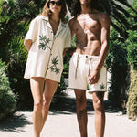 man and woman look at camera with palm trees in background