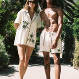 man and woman look at camera with palm trees in background