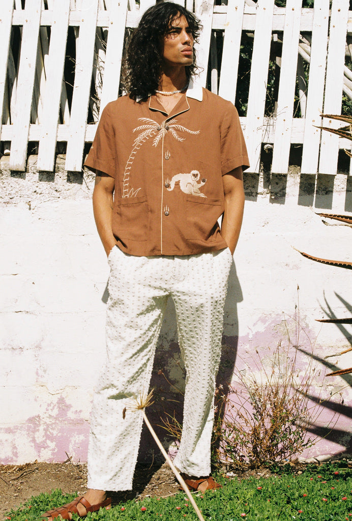 male model in monkey business tee posing in front of a fence